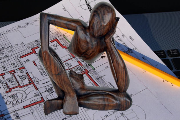 Nachdenkende Holzfigur auf Bauplan