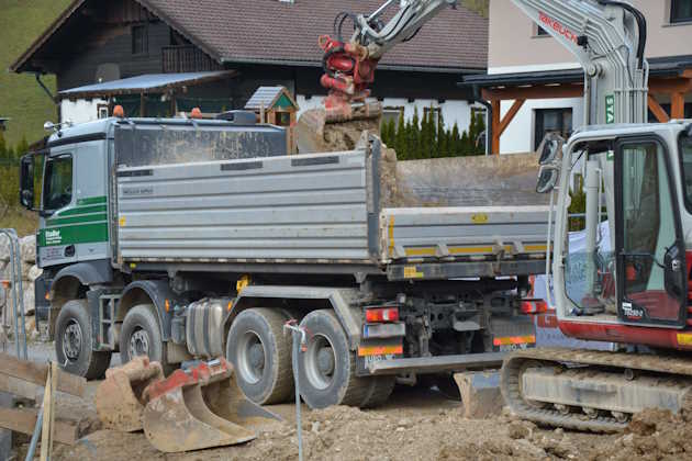 Bagger beim Beladen von LKW mit Aushubmaterial für Abtransport