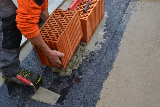 Maurer beim Ansetzen von Mauerwerk mit HLZ 25 cm