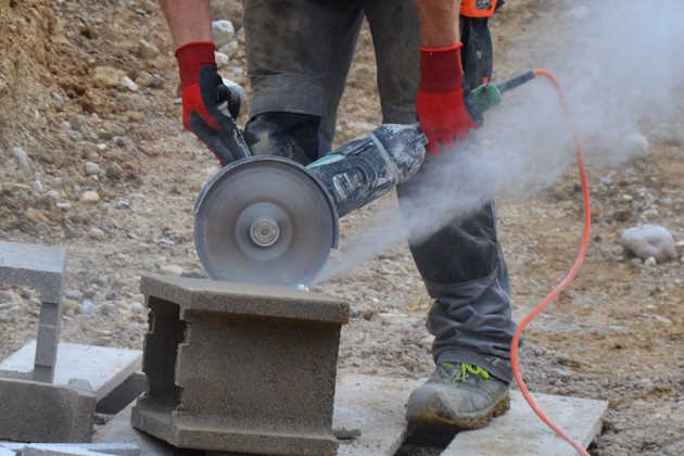 Arbeiter mit Flex beim Ziegelschneiden