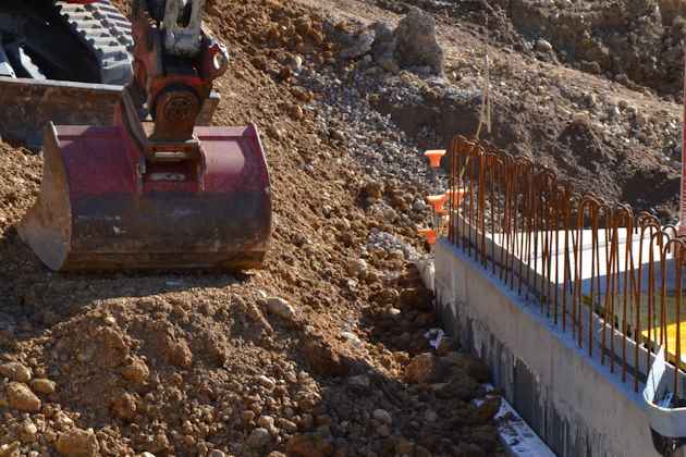 Bagger beim Hinterfüllen eines Betonbauwerks mit Aushubmaterial (Bild: © bauimbild.com)