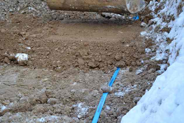 Eingebautes Kabelwarnband wird von Bagger mit Schotter überschüttet