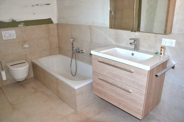 Badezimmer mit weißer Sanitärkeramik WC, Badewanne und Waschtisch